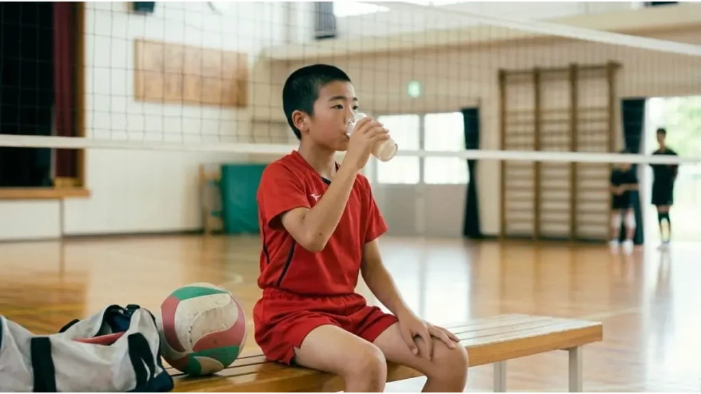 体育館でバレーボール練習後、栄養補給をする中学生男子