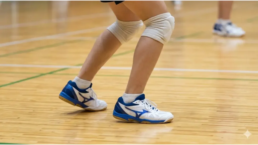 体育館の木床に安全に着地する中学生バレーボール選手の足元。膝と股関節を曲げて衝撃を吸収している。
