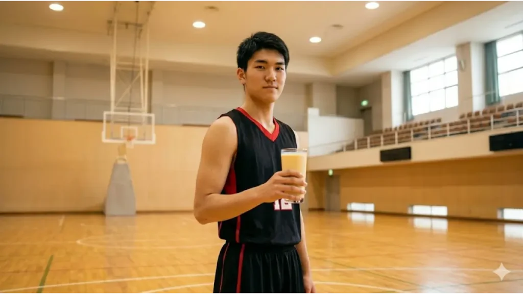 バスケコートを背景に、成長期とパフォーマンス維持のための栄養ドリンクを手にする日本人アスリート