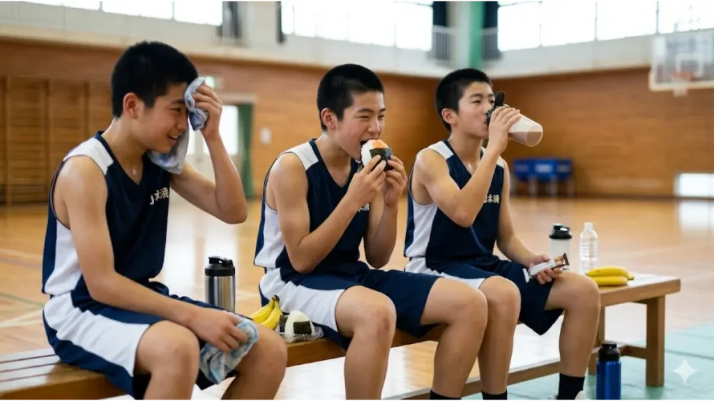 バスケ部朝練の直後にベンチでおにぎり、バナナ、プロテインを摂取する日本人の選手たち。最強のリカバリー飯。